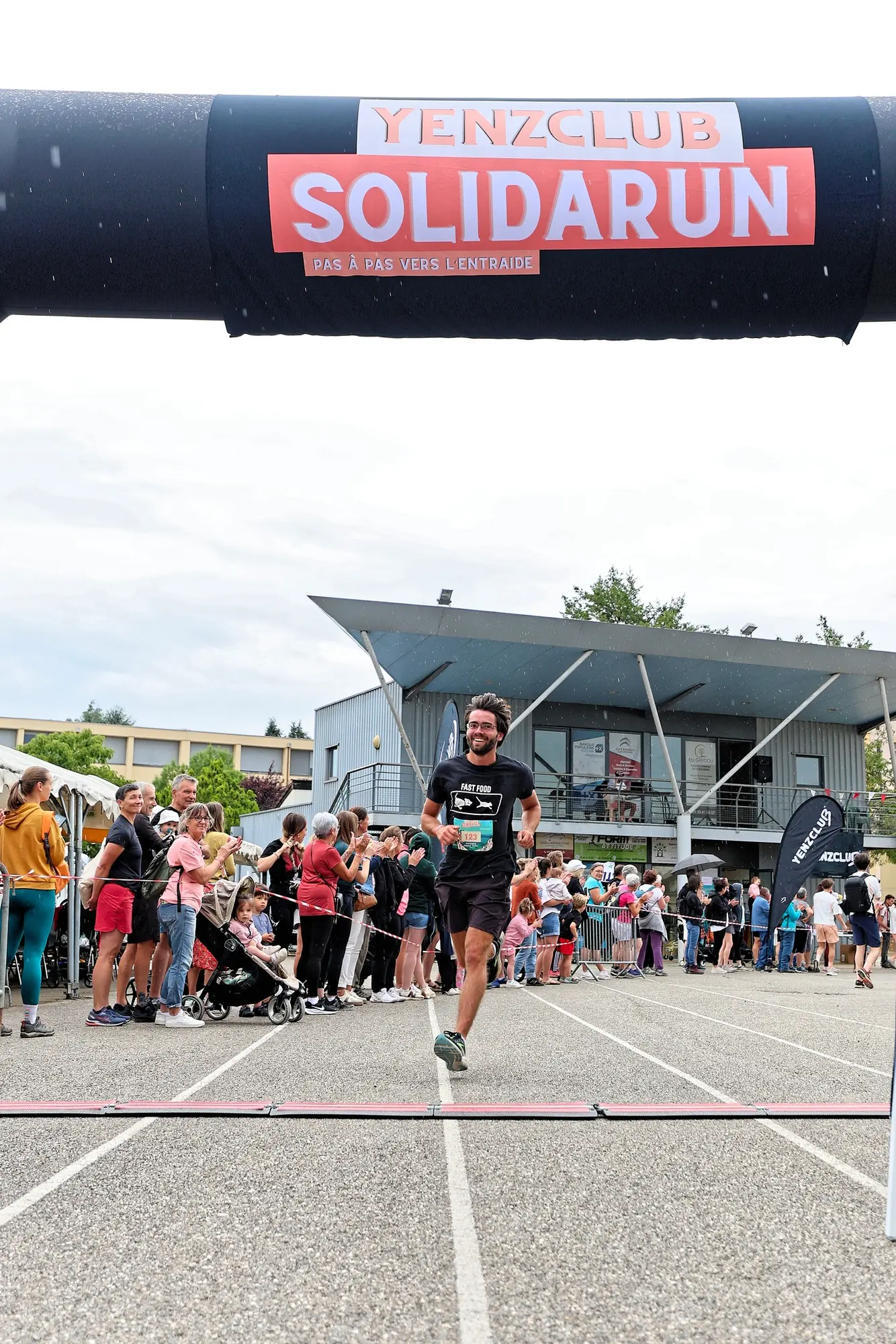 Un coureur franchit la ligne d'arrivée sous l'arche, les spectateurs applaudissent